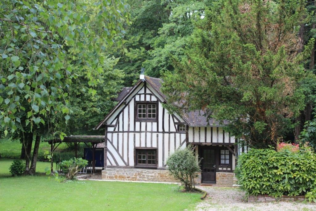 a black and white house in a garden at Les Chenes, avec piscine, tennis et lac privatif in Guerquesalles