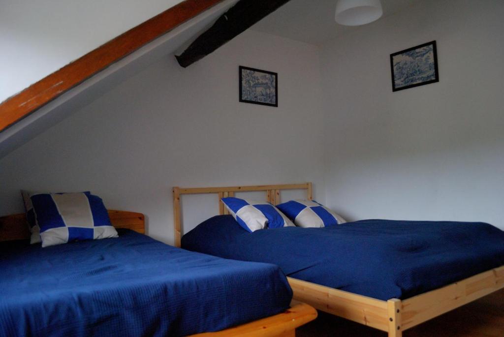 2 letti in una camera da letto con lenzuola e cuscini blu di Freedomus Marne-La-Vallée "Crécy" a Crécy-la-Chapelle