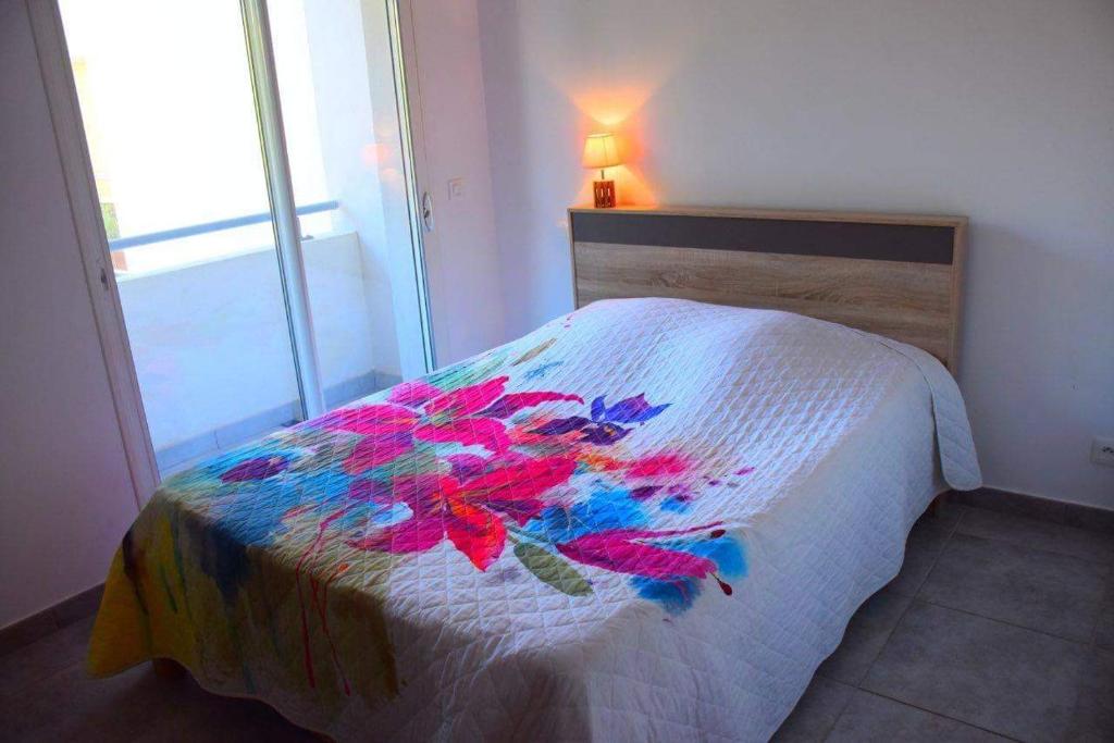 - une chambre avec un lit doté d'une couette en fleurs dans l'établissement Appartement l'Orangeraie, à Calvi