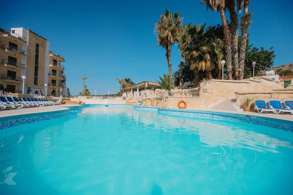 圣保罗湾城Xemxija Bay Hotel的一个配有椅子和棕榈树的大型游泳池