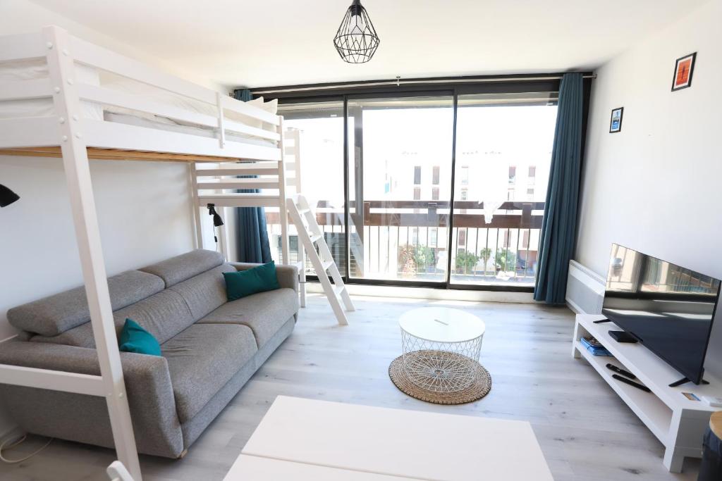 - un salon avec un canapé et des lits superposés dans l'établissement Appart lumineux et climatise St Cyprien 3 min du port, à Saint Cyprien Plage