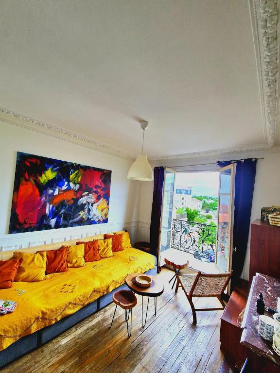 un salon avec un canapé jaune et un tableau mural dans l'établissement Grand F2 Roland Garros Paris Auteuil, à Boulogne-Billancourt