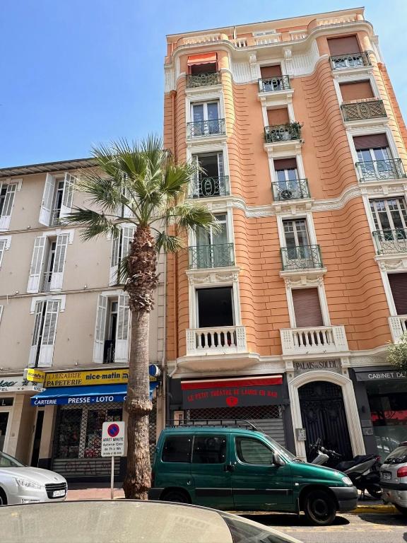 une camionnette verte garée devant un grand immeuble dans l'établissement Palais du Soleil vacances dans un immeuble art déco, à Antibes