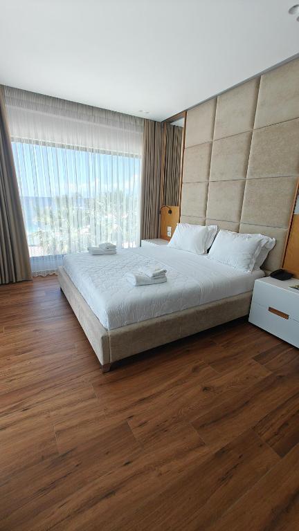 a bedroom with a large bed and a large window at King Hotel Ksamil in Ksamil