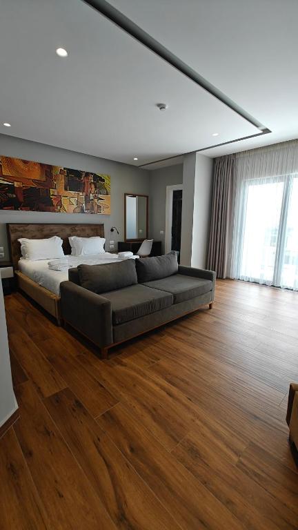 a large bed in a large room with wood floors at King Hotel Ksamil in Ksamil
