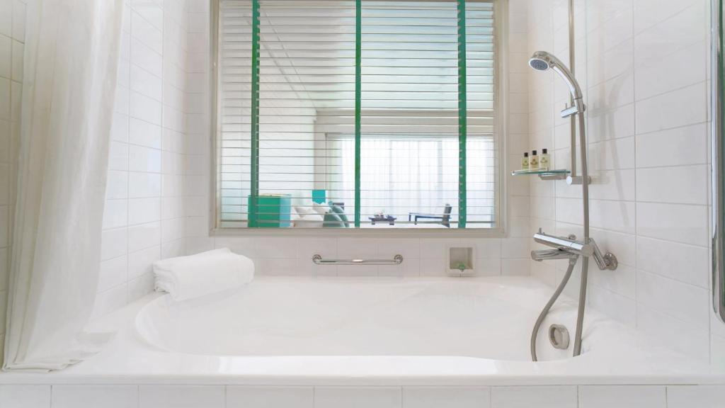 a white bathroom with a shower and a tub at ANA InterContinental Manza Beach Resort by IHG in Onna