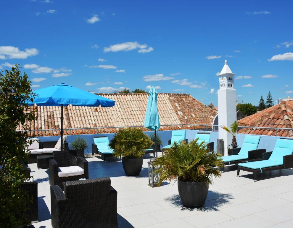 a patio at a hotel with chairs and a lighthouse at Tavira House in Tavira