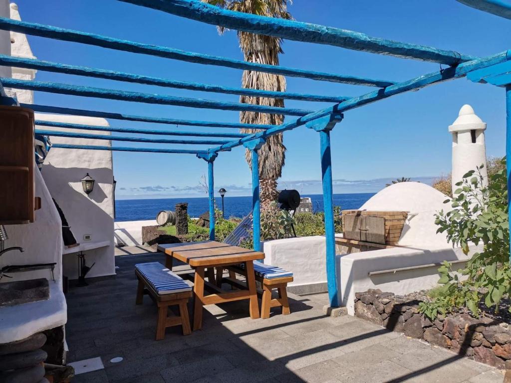 eine Terrasse mit Tisch und Stühlen und dem Meer in der Unterkunft Villa Exclusiva en El Hierro con Piscina Privada in Las Puntas