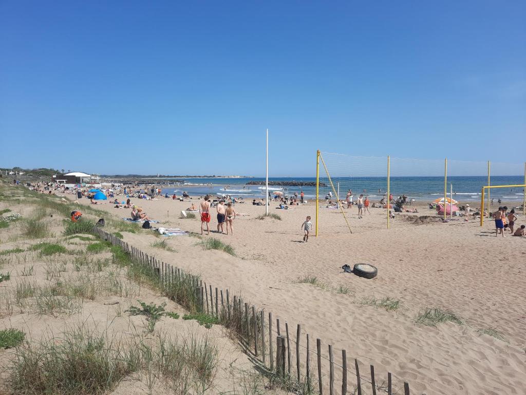 un groupe de personnes sur une plage avec une clôture dans l'établissement Appartement neuf et climatisé, 4 personnes, à 150m de la plage, à Vias