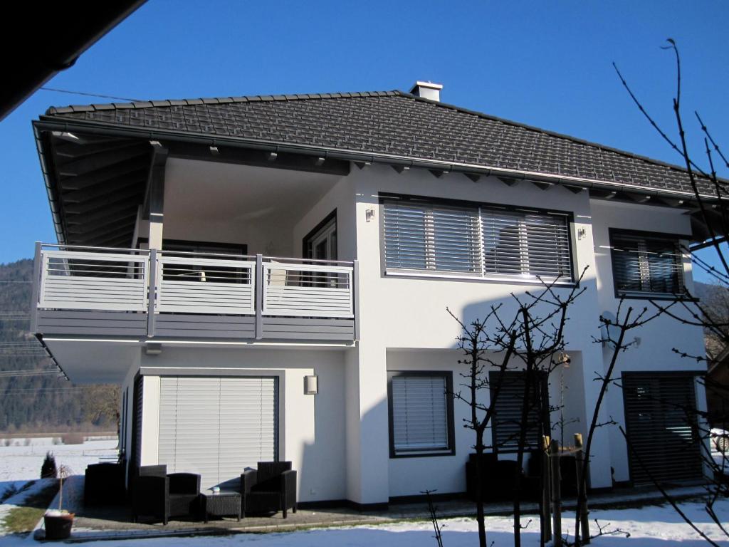 a white house with a balcony and a garage at Apartment Mitterberger - Nassfeld in Tröpolach