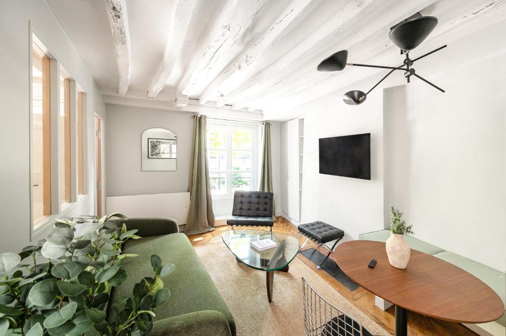 un salon avec un canapé vert et une table dans l'établissement Elegant Parisian apartment, Place des Vosges, à Paris