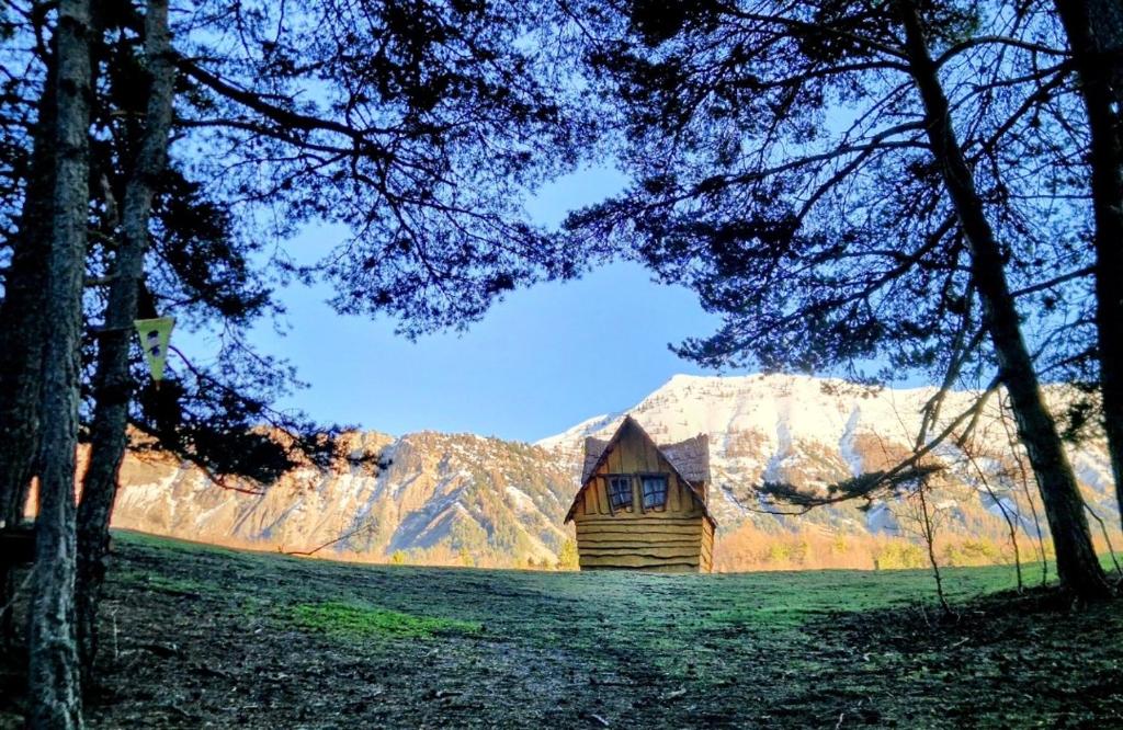 une cabine dans un champ avec des montagnes en arrière-plan dans l'établissement La cabane enchantée, Logement Insolite à La Ferme, à Le Vernet