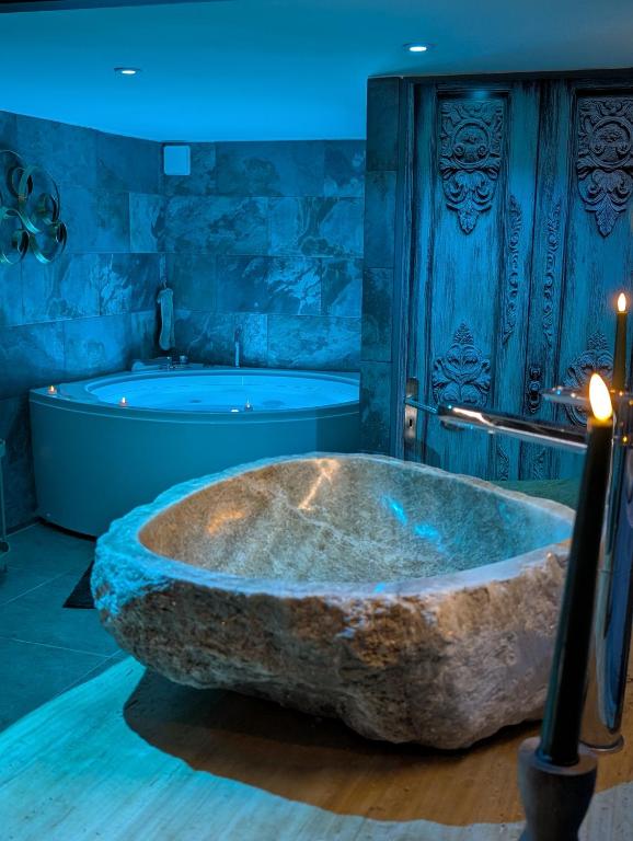 une grande baignoire en pierre dans une salle de bain avec baignoire dans l'établissement Maison Insolite avec Spa Privatif, à Monbalen