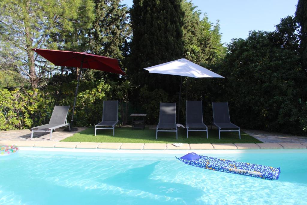 - une piscine avec des chaises et un parasol dans l'établissement La villa des six ifs - La glycine, à Flayosc