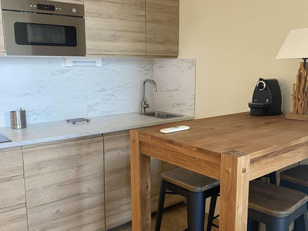 - une cuisine avec une table en bois et un évier dans l'établissement Appartement 4 pers, balcon sud, quartier Passeaux - Alpe d'Huez - FR-1-405-111, à L'Alpe-d'Huez