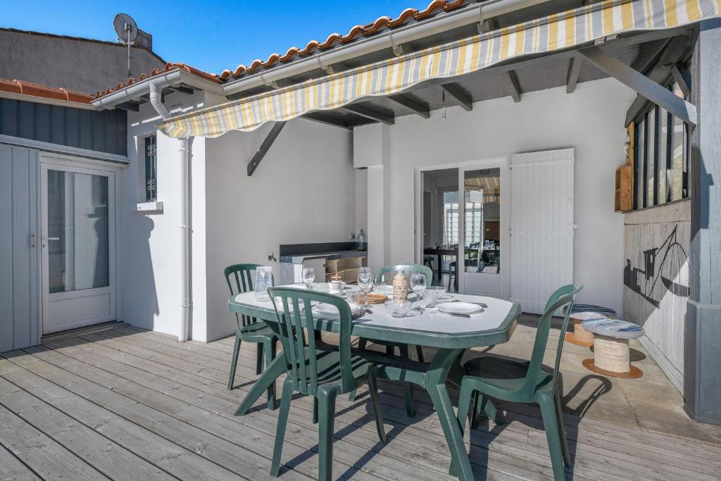 eine Terrasse mit Tisch und Stühlen auf einem Deck in der Unterkunft À 300m de la mer maison - jardin - Piscine pour 4 in Sainte-Marie