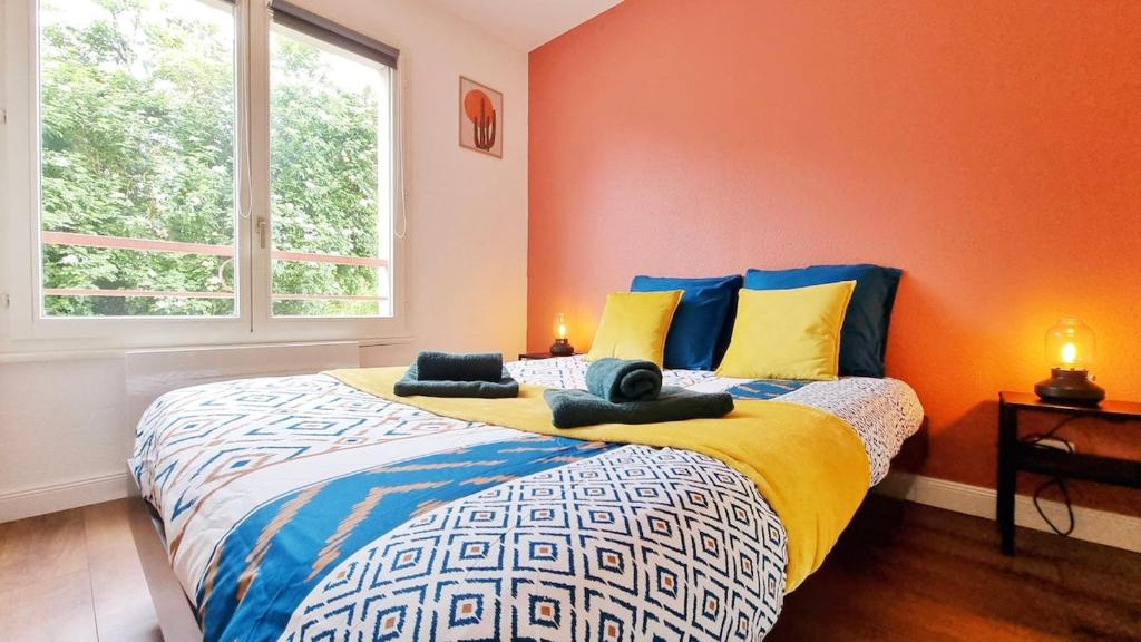 une chambre avec un grand lit aux murs orange dans l'établissement Cocon Design & Confortable - Parking - RBNB, à Colmar