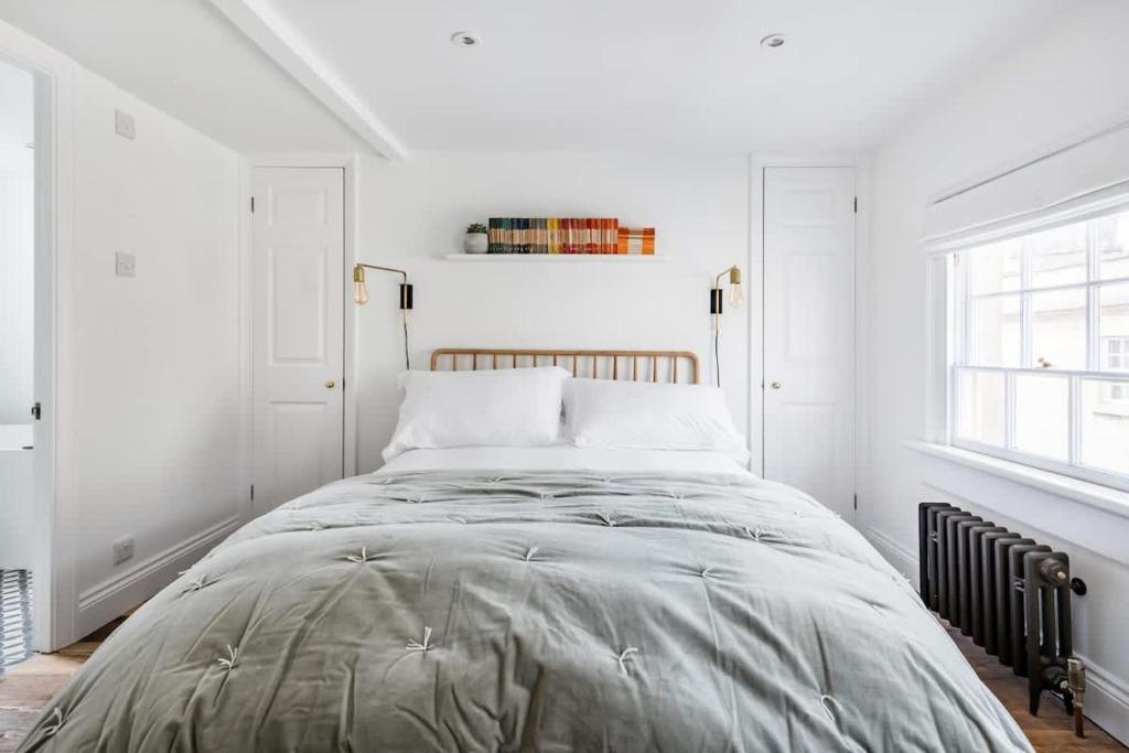 a bedroom with a large bed with white walls at Central Georgian Townhouse with Free Parking in Bath