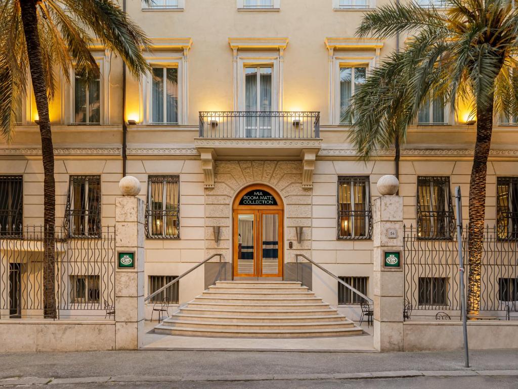 a building with stairs and a door and palm trees at Room Mate Collection Mia, Rome Colosseum in Rome