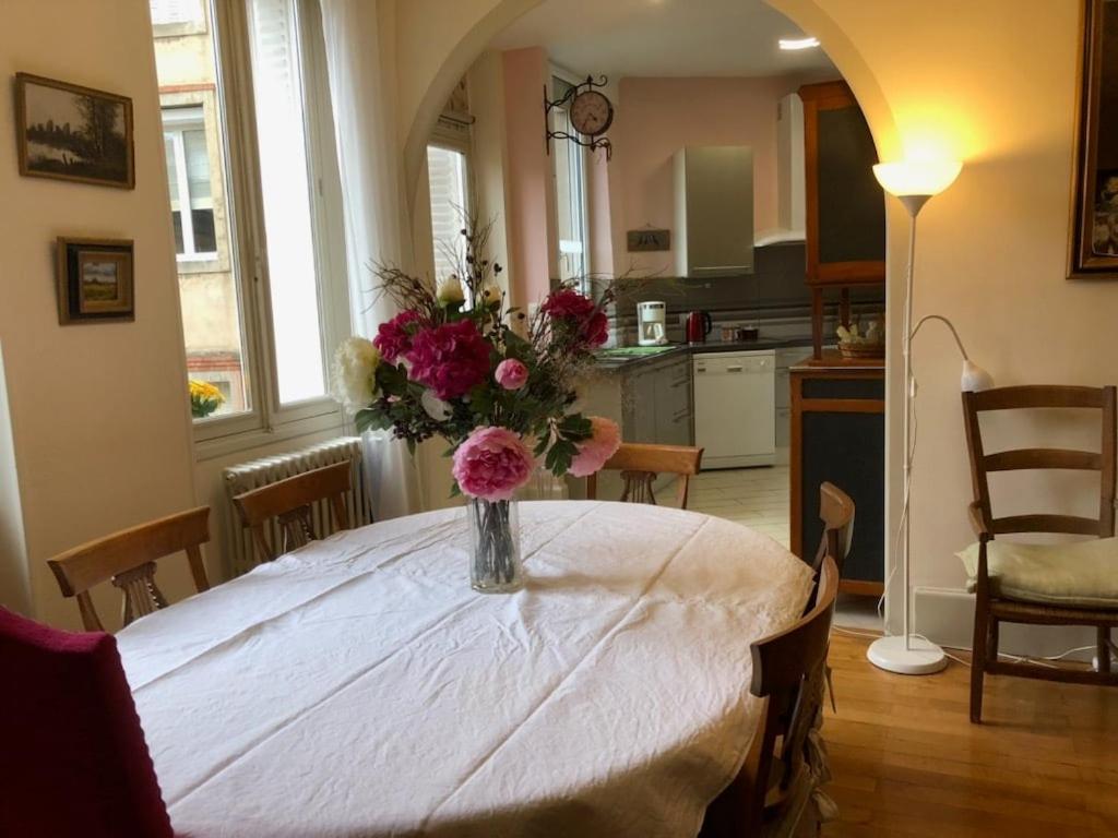une table de salle à manger avec un vase de fleurs dessus dans l'établissement Appartement de caractère au cœur de Poitiers, à Poitiers
