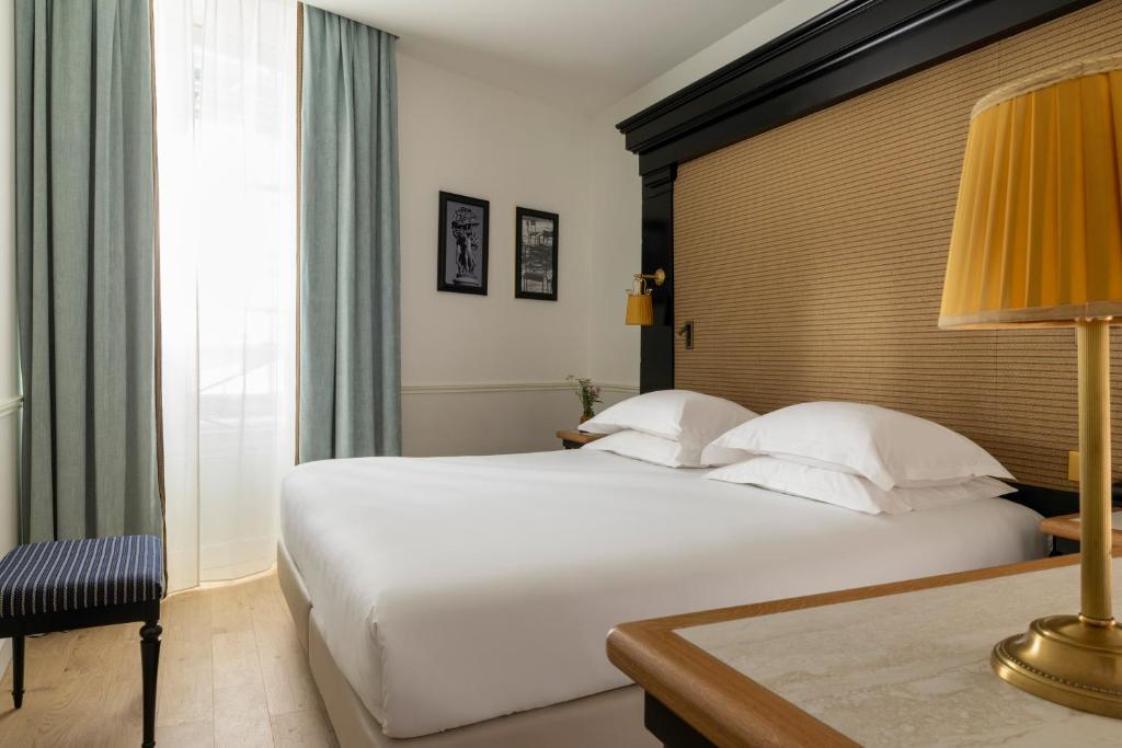 une chambre avec un grand lit blanc et une lampe dans l'établissement Hotel Observatoire Luxembourg, à Paris
