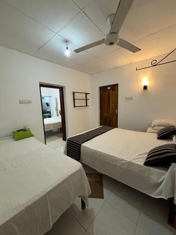 1 dormitorio con 2 camas y espejo. en Goalma Family Holiday Resort & Restaurant, en Anuradhapura