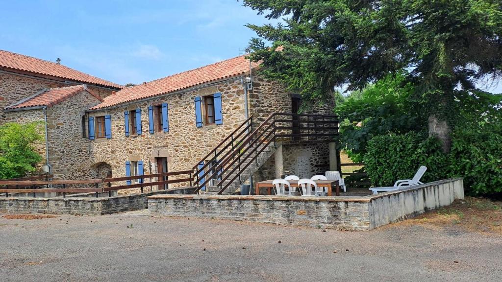 a stone house with a staircase and chairs in front of it at La nougarede in Jouqueviel