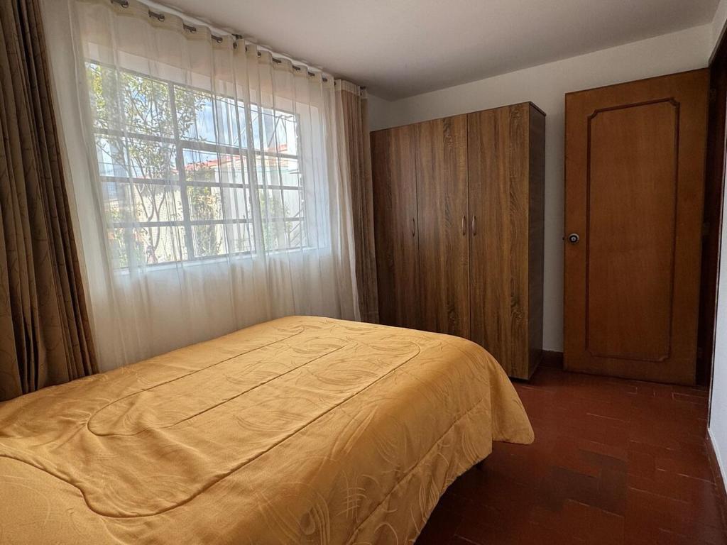 Un dormitorio con una cama amarilla y una ventana. en Omar J House, en Paipa