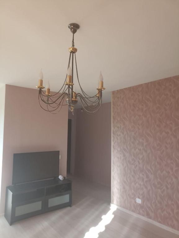 un lampadario a braccio in un soggiorno con camino di Divu istabu saulains dzīvoklis Ugālē a Ugāle