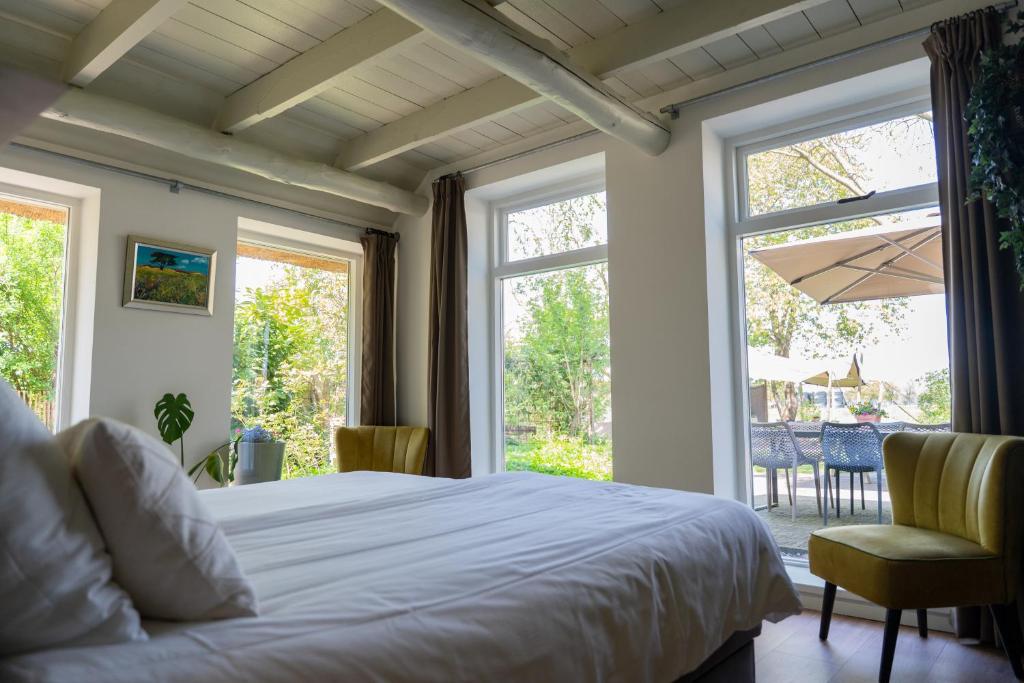een slaapkamer met een bed en een groot raam bij Bed & breakfast De Loeghoeve in Anderen
