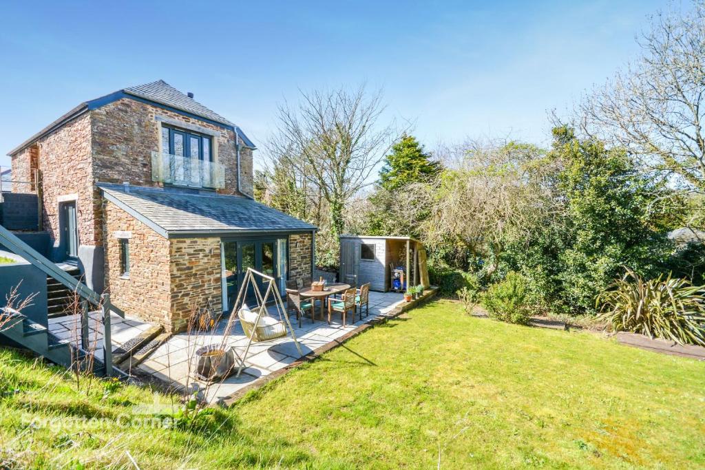 a brick house with a deck in the yard at Wiggle Barn in Torpoint