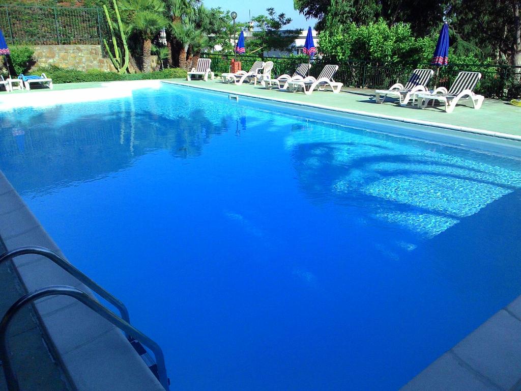 a large blue swimming pool with lounge chairs andorians at Residence La Carruba in Diano Marina