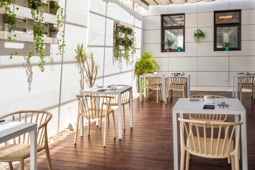 a restaurant with tables and chairs and plants at Catalonia Málaga in Málaga