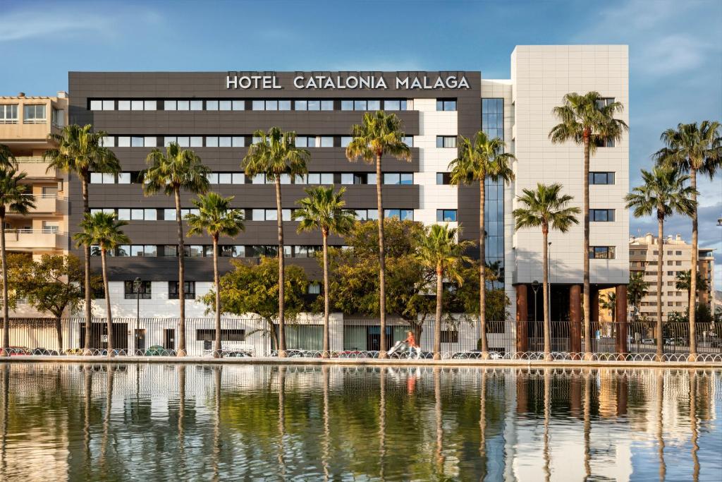 a hotel with palm trees in front of a building at Catalonia Málaga in Málaga