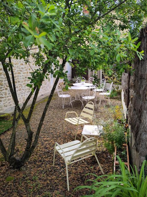 une terrasse avec une table et des chaises sous certains arbres dans l'établissement L'ENVOLEE, à Champdeniers