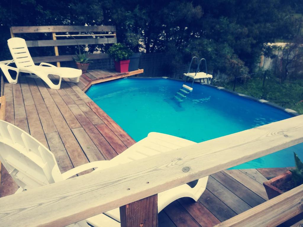 une piscine sur une terrasse en bois avec deux chaises et un banc dans l'établissement Jolie rez de villa avec piscine à 16km d ajaccio, à Peri
