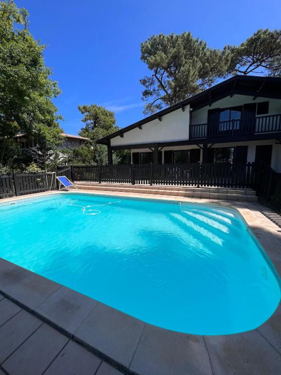 une grande piscine bleue devant une maison dans l'établissement Bask'aise o Pyla, à La Teste-de-Buch