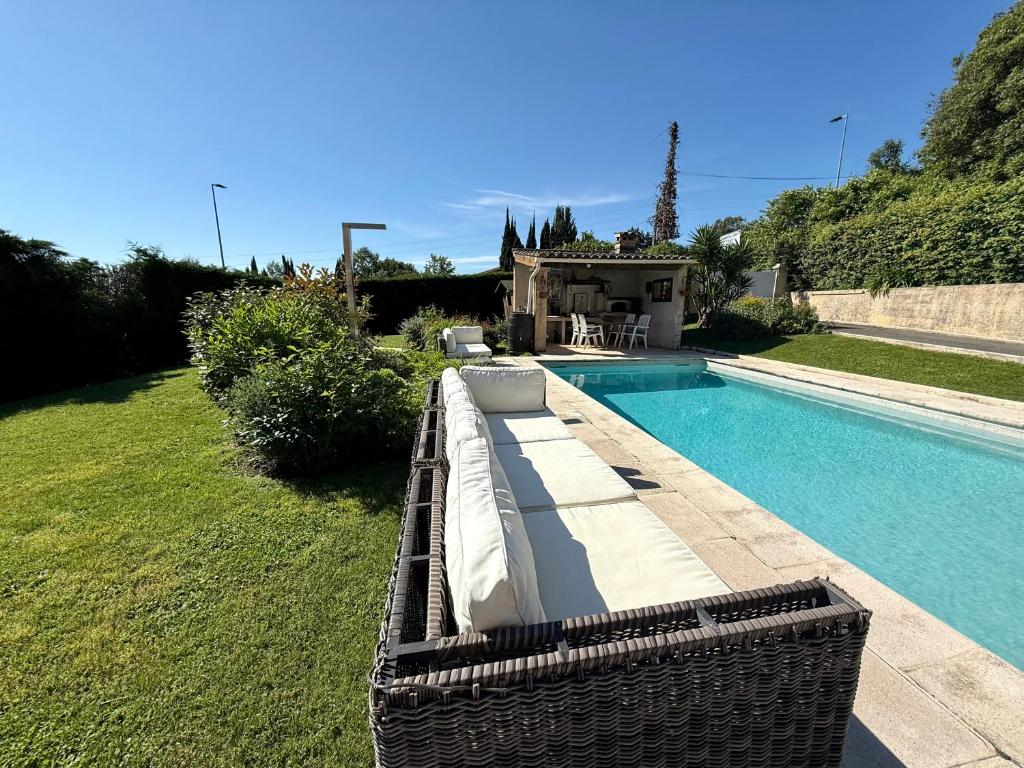 une piscine avec une chaise longue en osier à côté d'une piscine dans l'établissement Un appartement 2 pièces dans une villa avec piscine et parking, à Vence