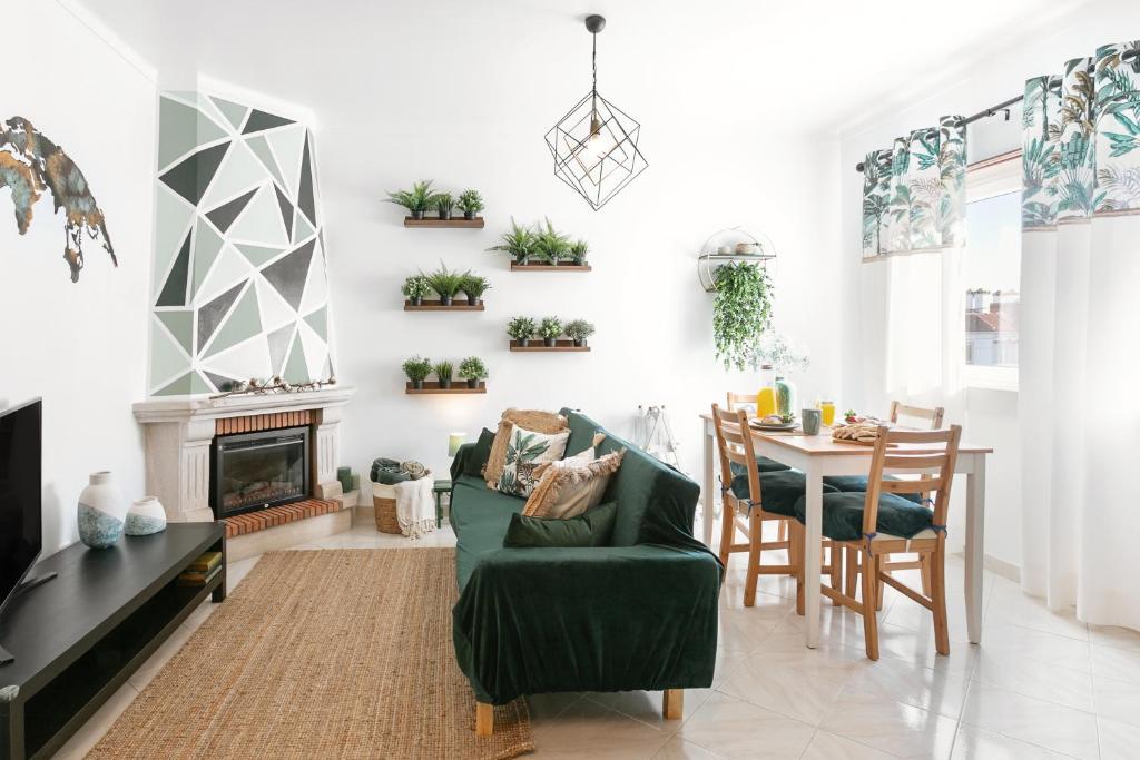 a living room with a green couch and a table at Vila Florida - T2 familiar perto da praia in São Martinho do Porto