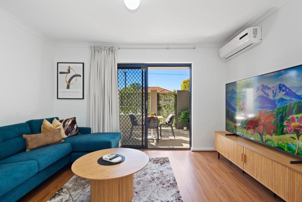 a living room with a blue couch and a flat screen tv at Comfort & Convenience - A Sepal Stay in Perth