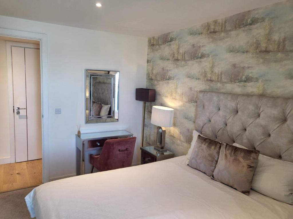ein Schlafzimmer mit einem Bett und einem Schreibtisch mit Spiegel in der Unterkunft Top floor luxury riverfront apartment in Woolwich