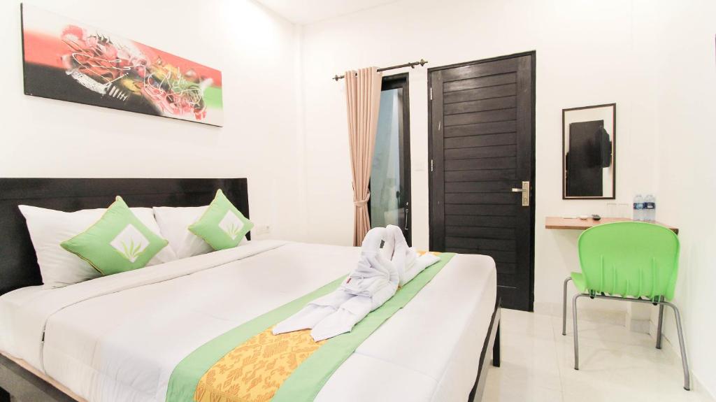 ein Schlafzimmer mit einem großen Bett und einem grünen Stuhl in der Unterkunft Akatara Stay in Jimbaran