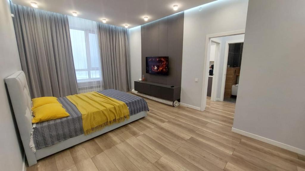 アスタナにある1-комнатная люкс квартира в районе Ханшатырのベッドとテレビのある寝室