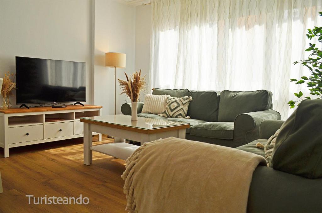 a living room with a couch and a tv at Apartamento Corimar - Céntrico y accesible para personas con movilidad reducida in San Vicente de la Barquera