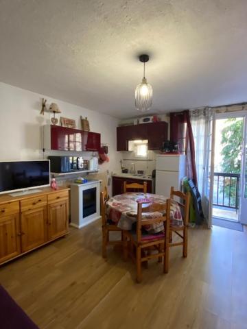 une cuisine avec une table et des chaises dans une pièce dans l'établissement Studio 2 à 4 personnes avec balcon et parking, à La Bourboule