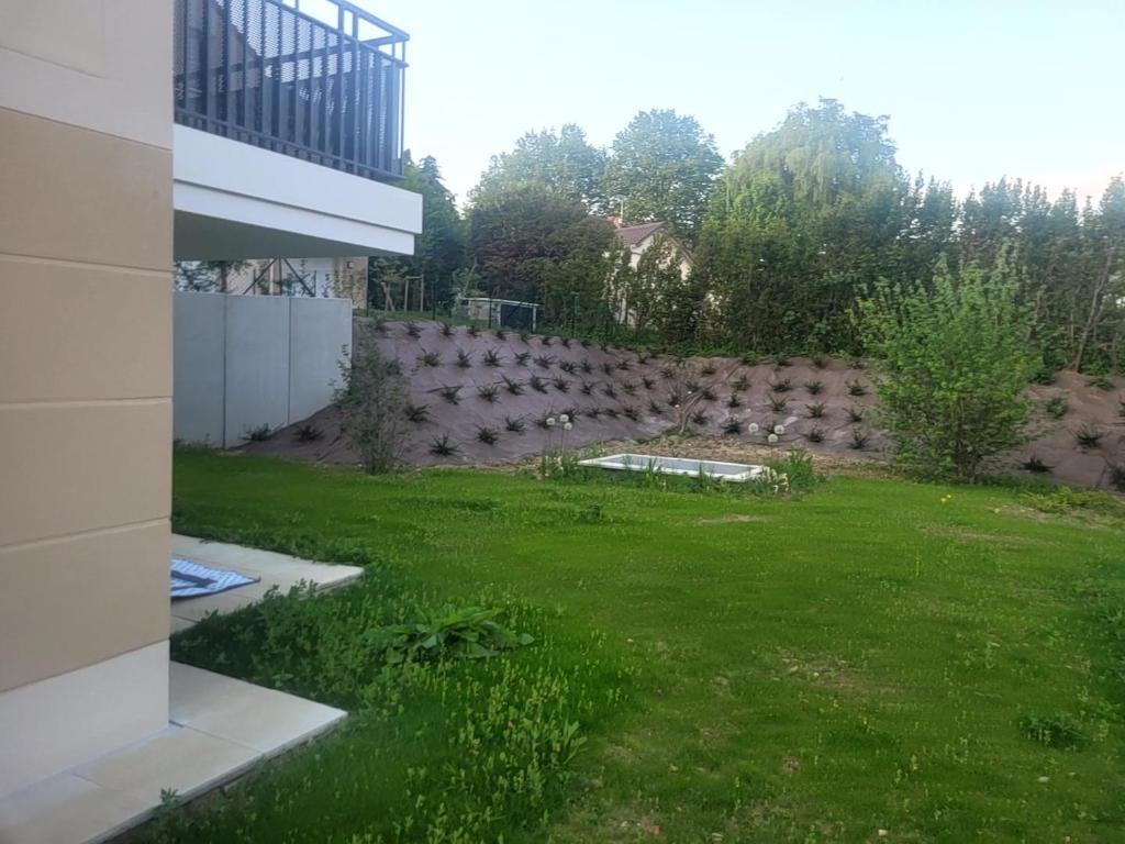 a backyard with a retaining wall and a green yard at Chambre d'hôte, dans 4 pièces , avec terasse, jardin in Saint-Witz