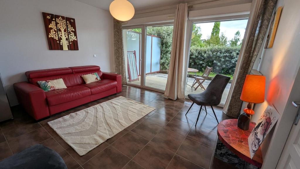 un salon avec un canapé rouge et une table dans l'établissement Terrace and apartment Between lake and mountain, à Annecy