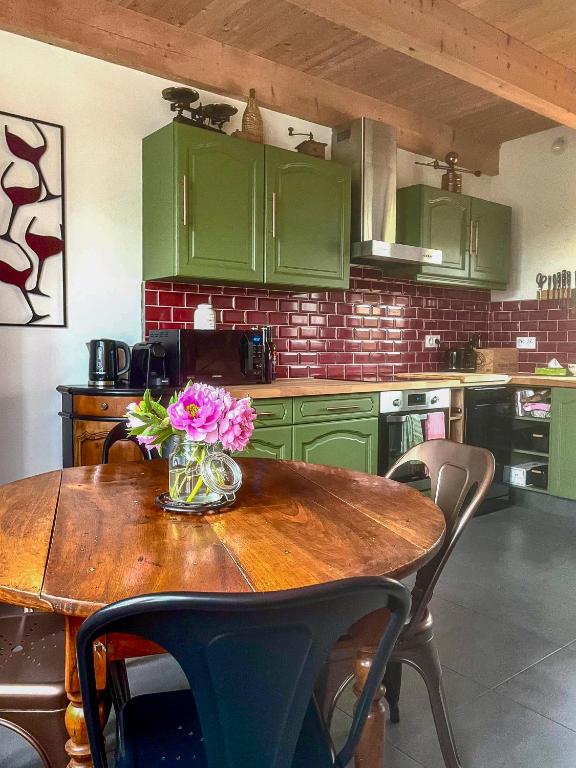 une cuisine avec des armoires vertes et une table en bois avec des fleurs dessus dans l'établissement Vignes et Sentiers Gîte de charme Bourgogne Sud, à Burnand