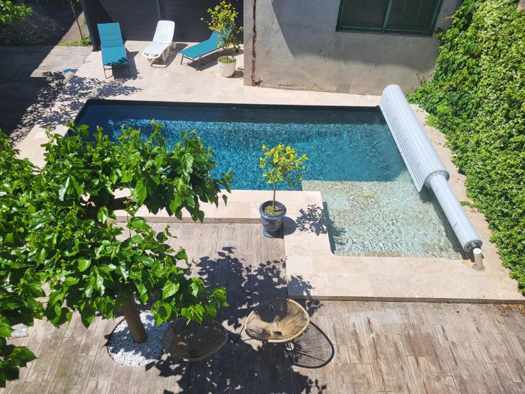 a swimming pool with potted plants on a wooden deck at Appartement avec piscine partagée in Boucoiran-et-Nozières