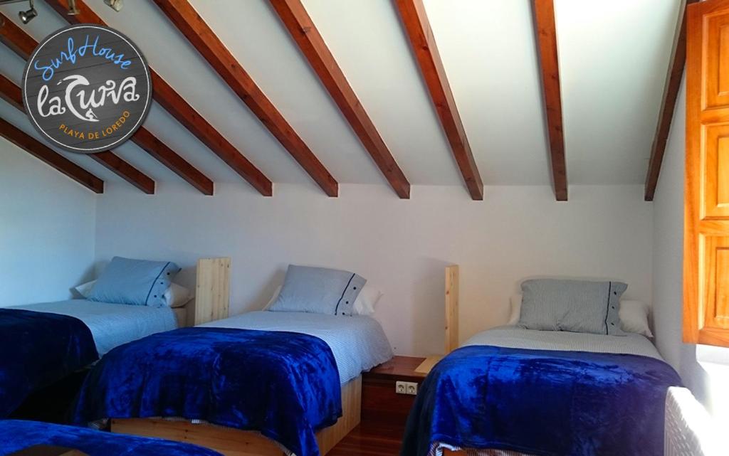 2 camas en una habitación con sábanas azules en La Curva Surfhouse, en Loredo